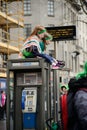 Two girls were sitting on the telephone booth on St. Patrick`s Day ParadeÃÂ in Dublin, Ireland, March 18th 2015